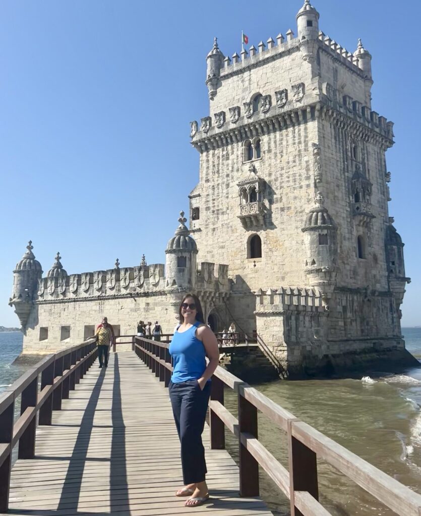 Kristie Rodriguez standing on the bridge in front of the Belem tower in Lisbon Portugal 