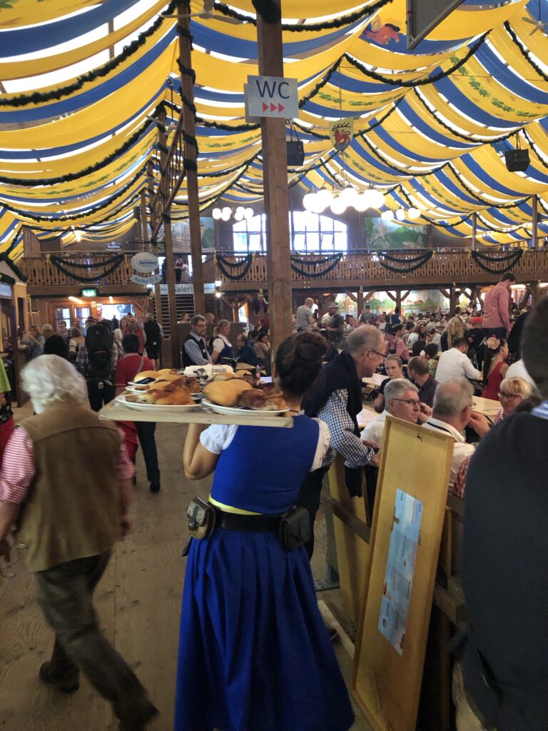 Inside a festival tent at Stuttgart volksfest in Bad Canstaat. A waitress carrying a tray of food. 