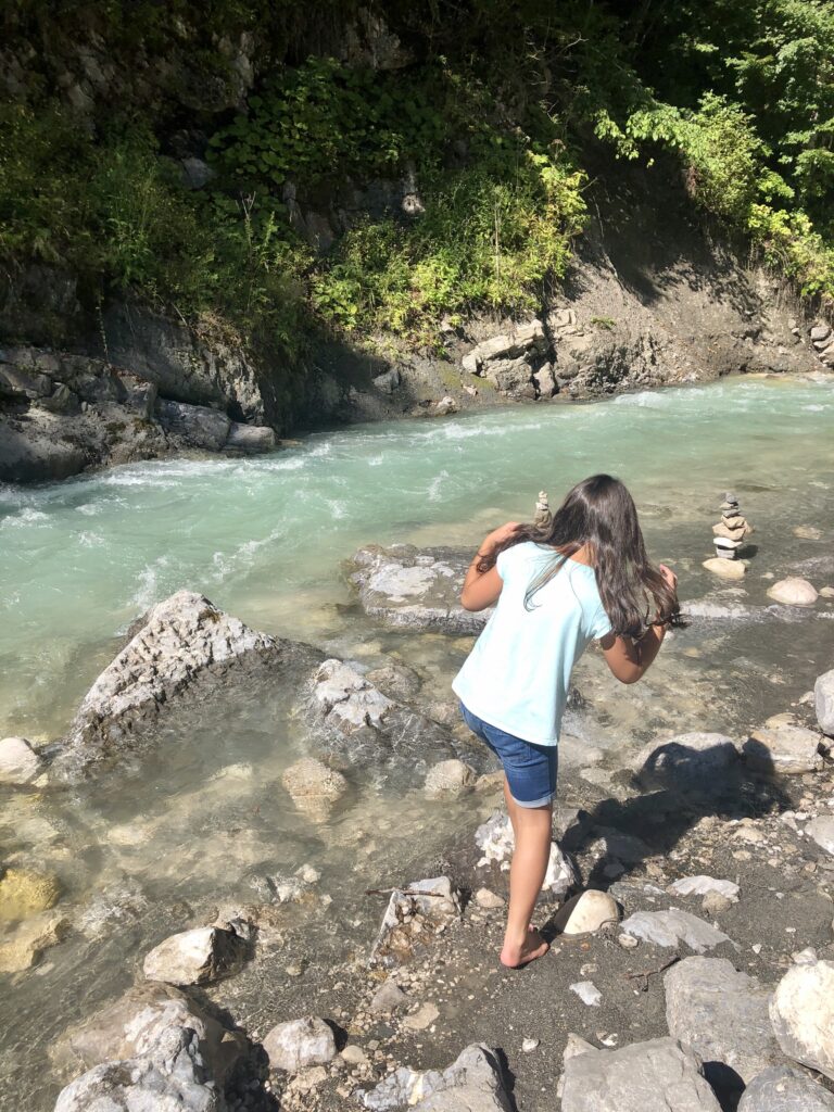 A young girl splashing in the blue Green waters of the Partnach River