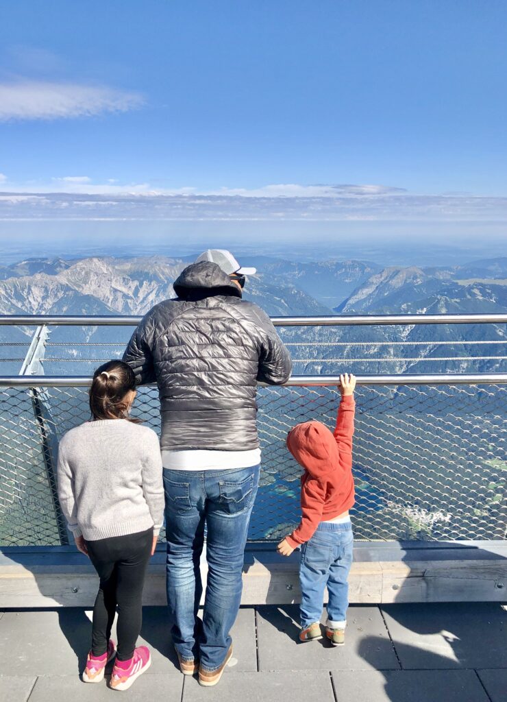 A father and his children taking in the mountain views at the top of Germany's highest mountain. the Zugspitze 