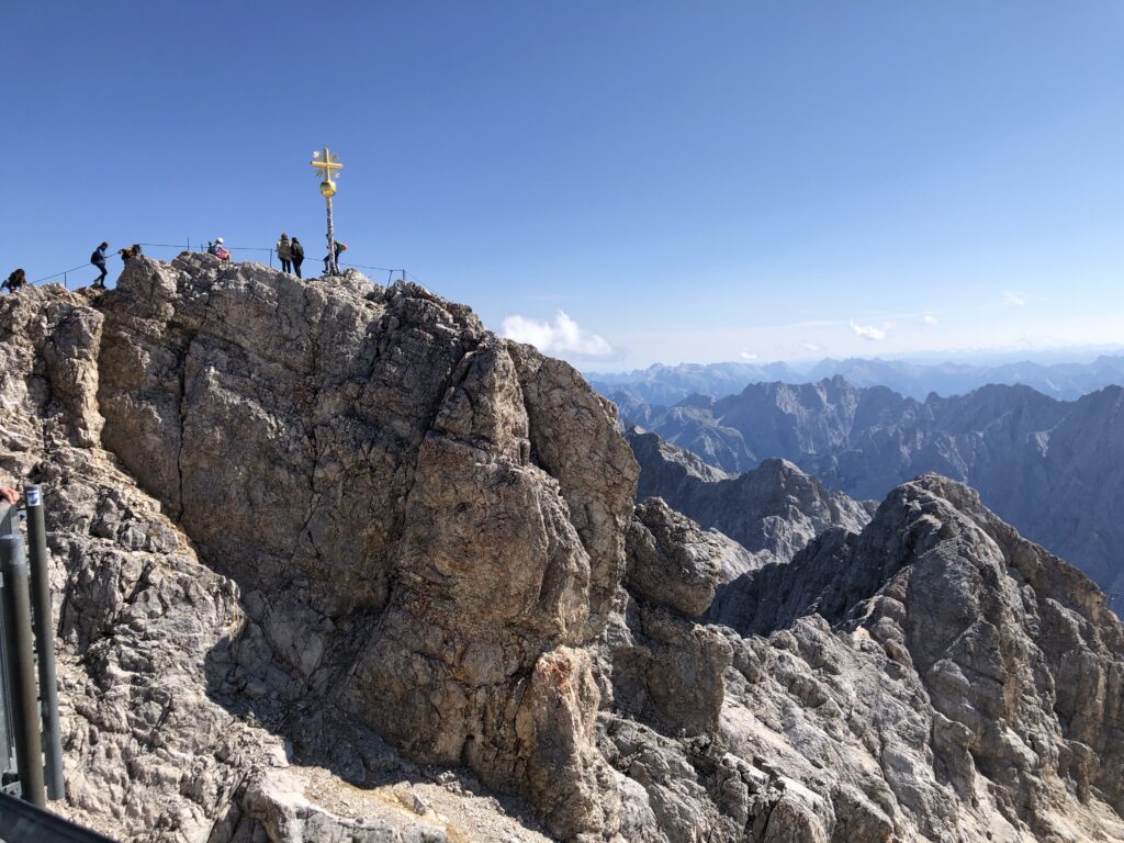 Hikers hike to the Golden Cross at the top of the summit of the Zugspitze in Germany. 