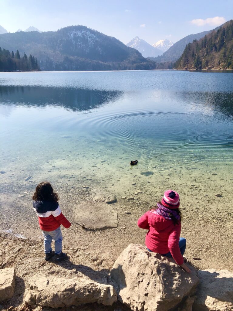 2 kids throwing rocks in the Alpsee, a lake near Neuschwanstein Castle in Bavaria, Germany. 